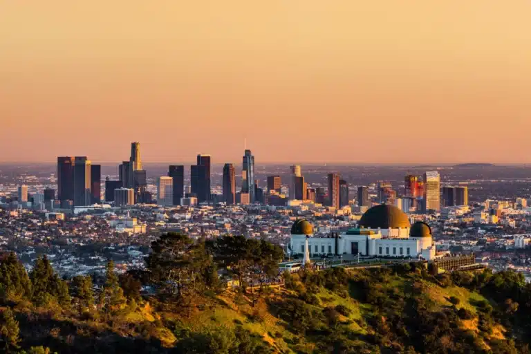 Los Angeles skyline at sunset with Griffith Observatory in the foreground.